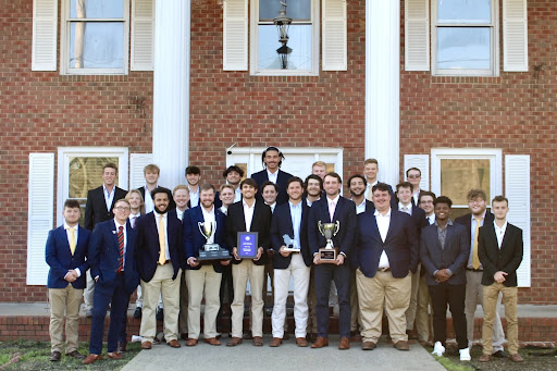 Men gathered around, posed in the front of the Pi Kappa Alpha house. 