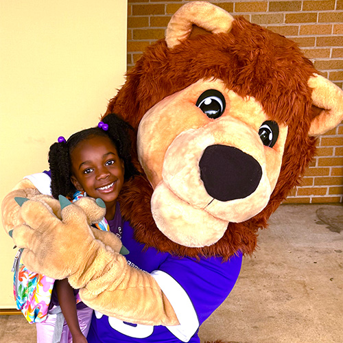 child hugging leo mascot in front of kilby