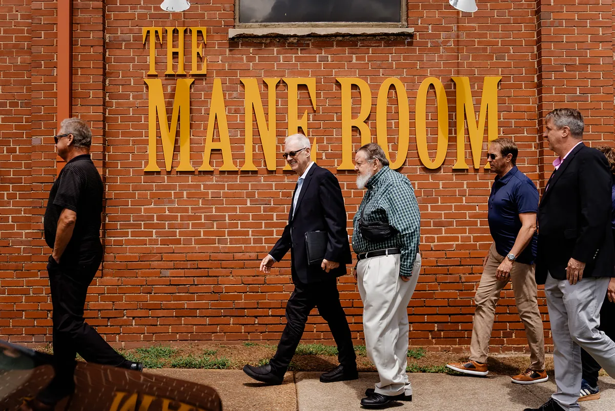 A group walking by The Mane Room sign