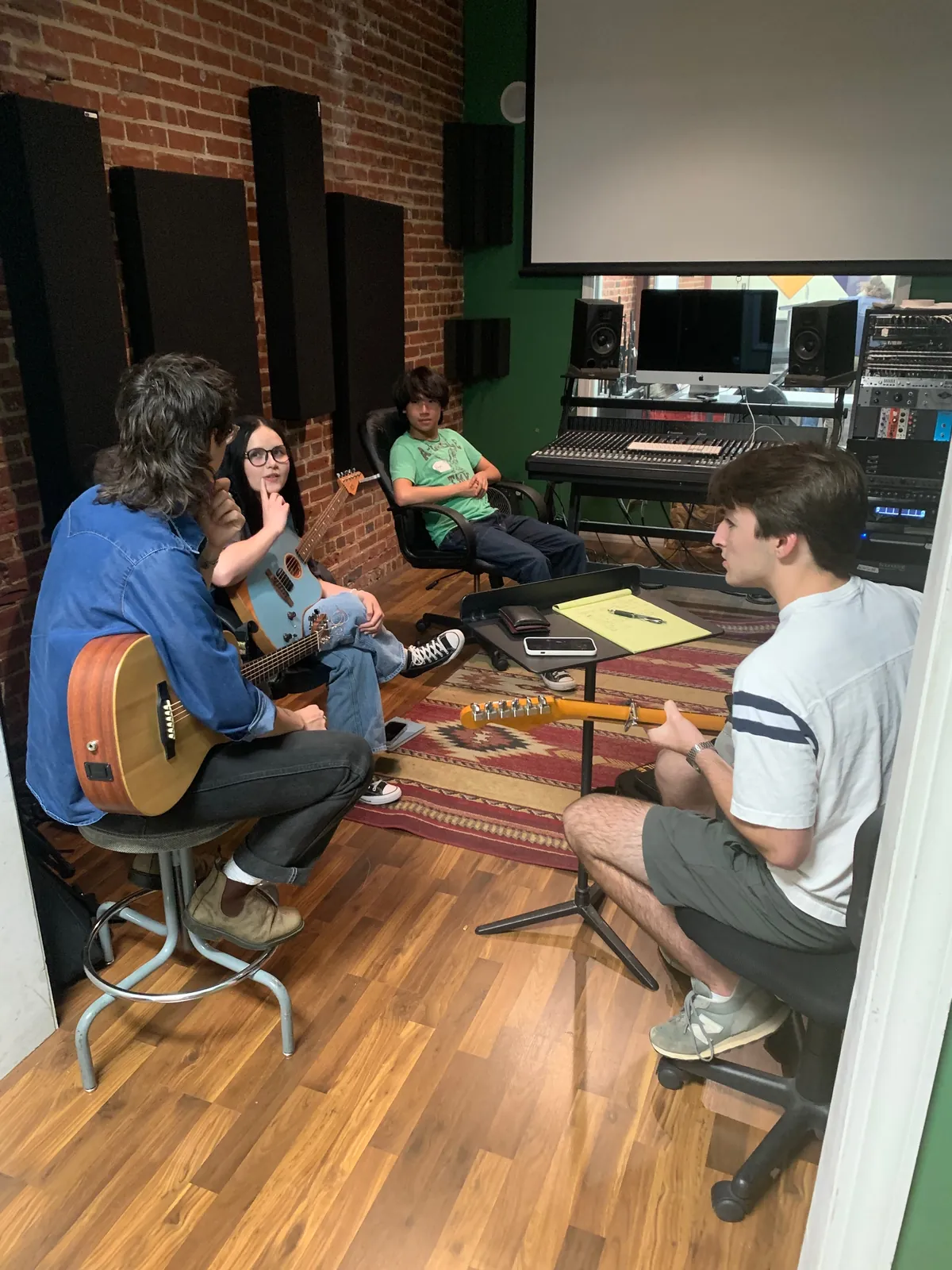 An individual with a guitar speaks to a group