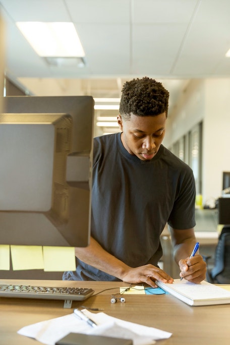 man taking notes near computer