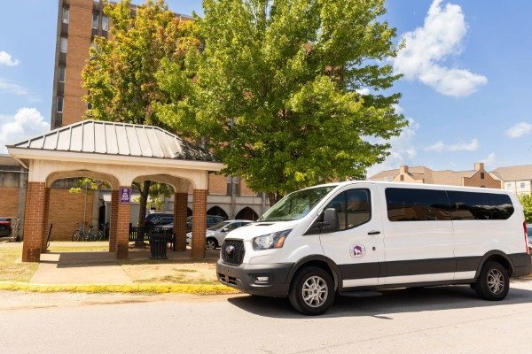 UNA shuttle van at the bus stop between Rice and Rivers Hall