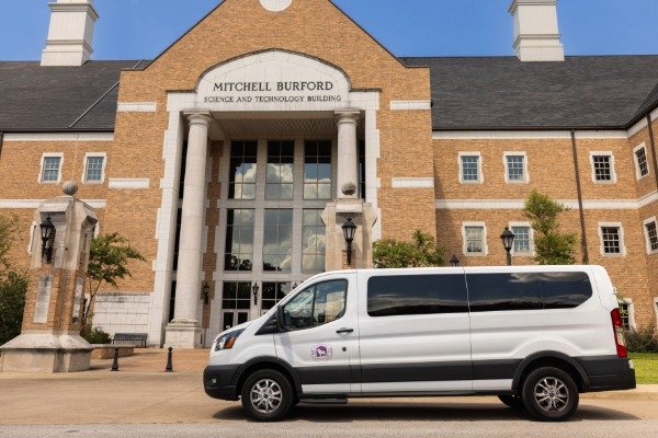 UNA shuttle van in front the Mitchell Burford Science and Technology Building