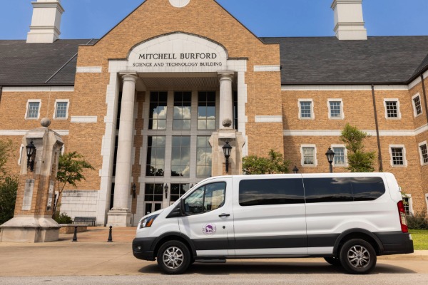 UNA shuttle van in front the Mitchell Burford Science and Technology Building
