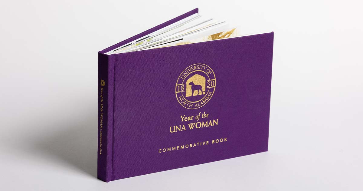 The Year of the UNA Woman Commemorative Book, a purple cloth hard-back book.