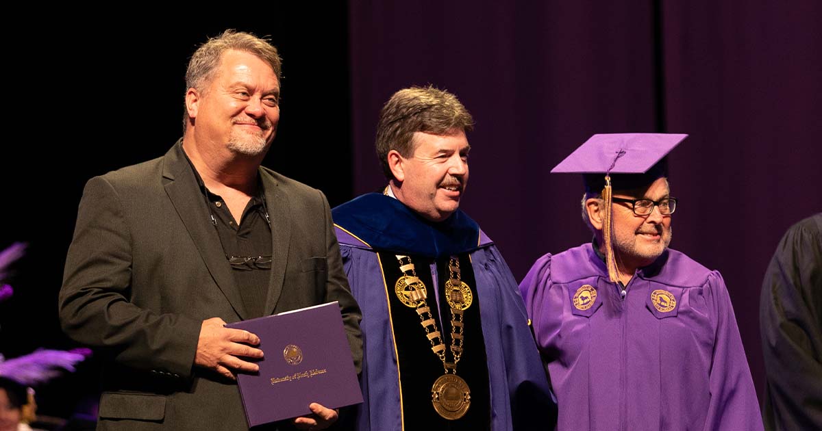 President Ken Kitts poses for a photo with Jay Johnson, son of the late Jimmy Johnson, and David Hood at the Fall 2021 commencement ceremony.