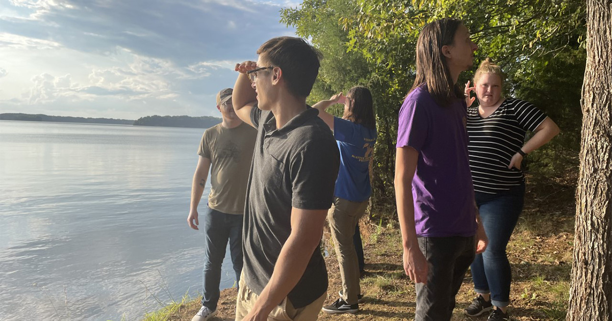 Students stand on the edge of the Tennessee River.