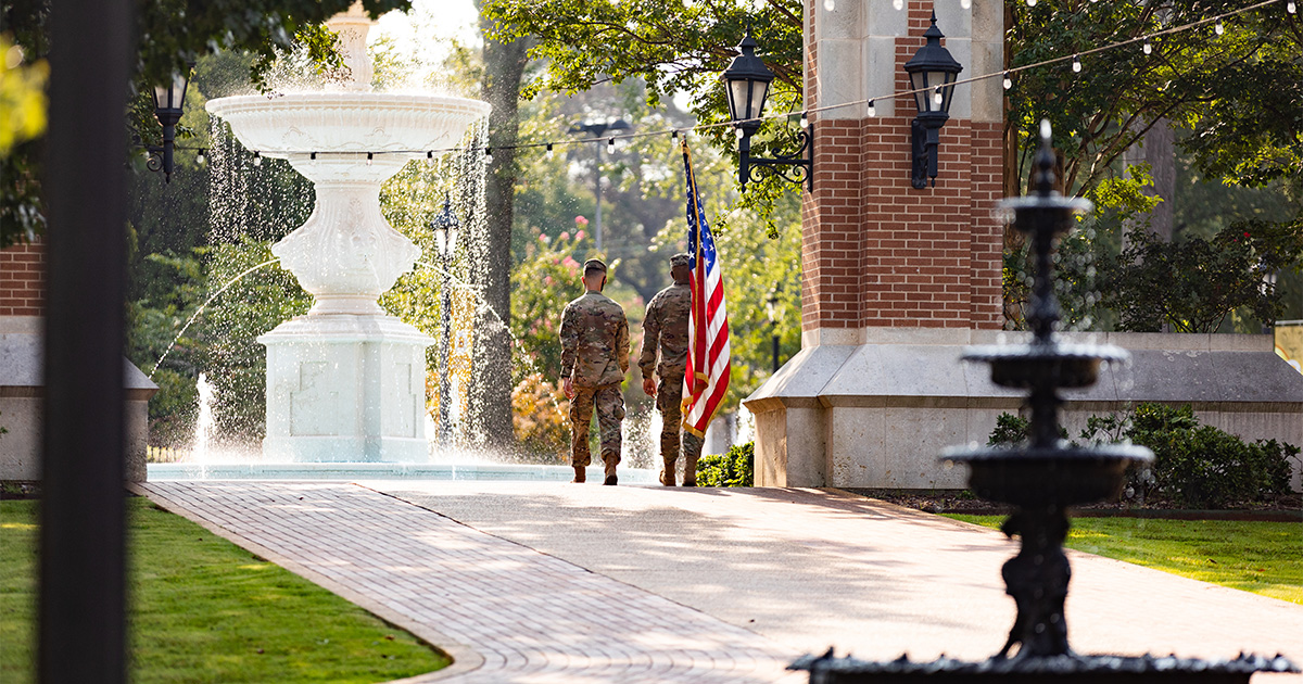 UNA ROTC members cross Harrison Plaza with the American Flag.