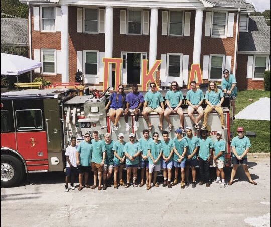 Fraternity members posed on a fire truck out front of the Pi Kappa Alpha house.