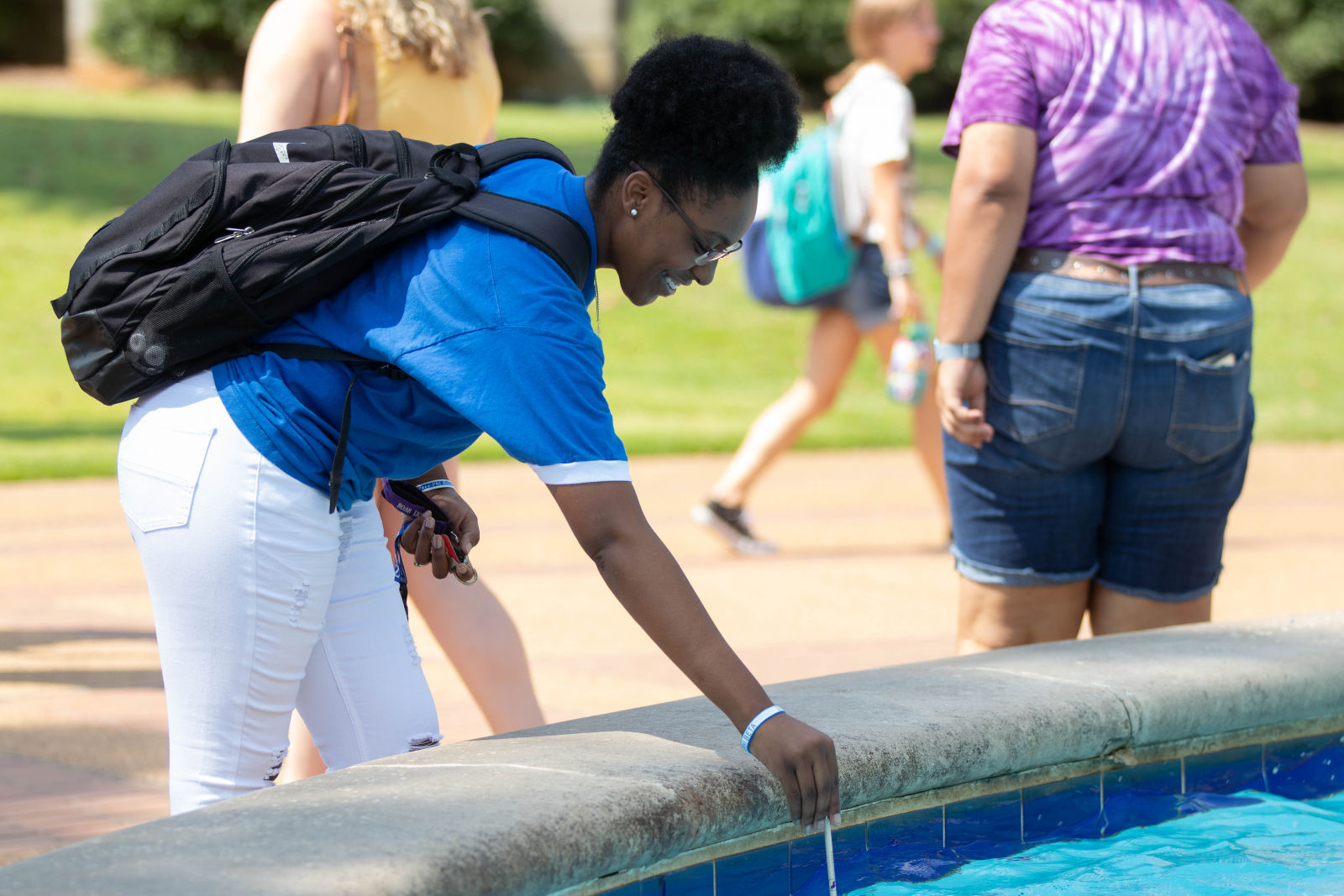 Student dipping their pencil in Harrison Fountain for good luck