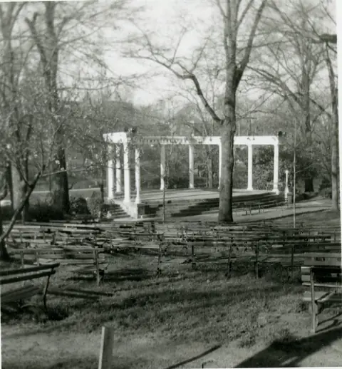 The Memorial Amphitheater&rsquo;s white colonnade stage, with rows of wooden benches on the slope below it