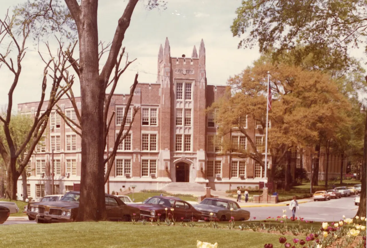 Bibb Graves Hall, a brick building with a castellated central tower, framed by trees and spring tulips