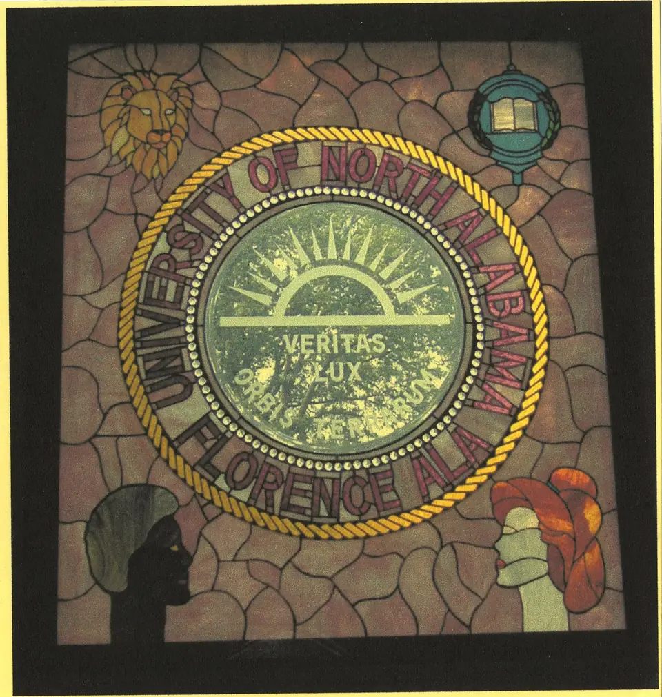 Stained-glass window of the University seal: a rising sun over the motto Veritas Lux Orbis Terrarum, ringed by the words University of North Alabama, Florence, Ala.