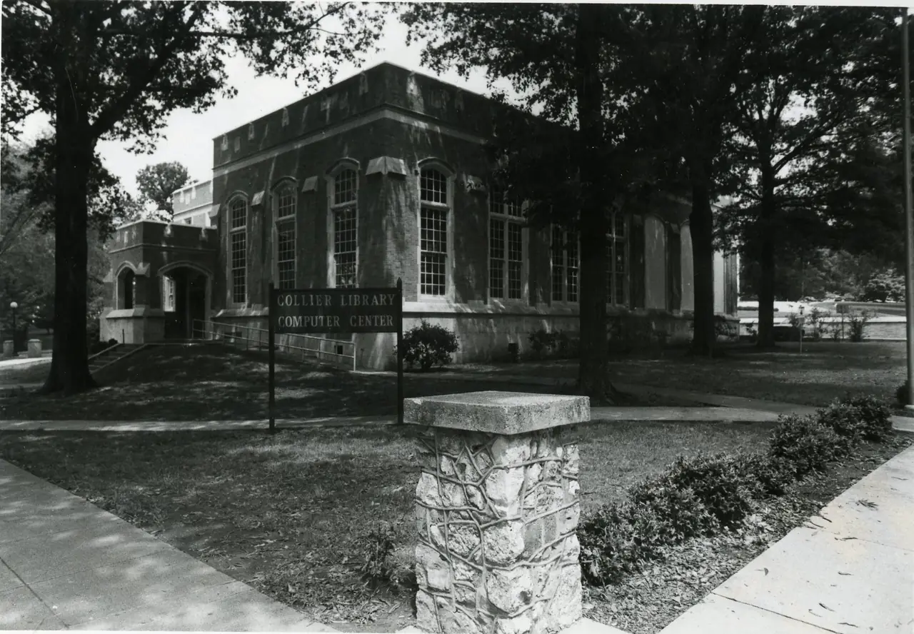 Collier Library, a brick building with tall arched windows, behind a sign reading Collier Library Computer Center