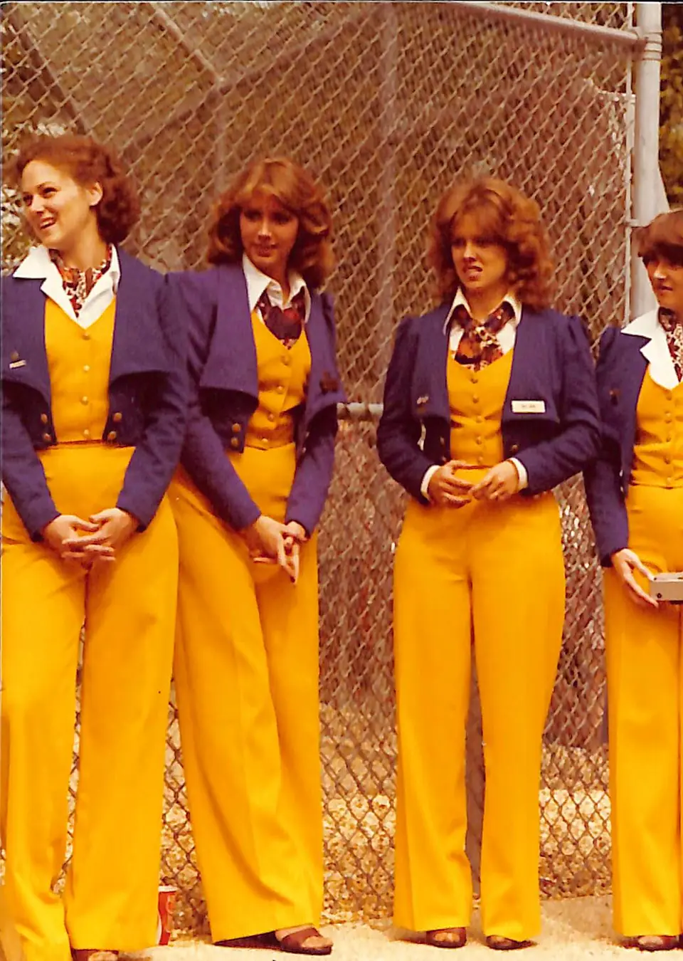 Four Golden Girls in gold trousers and vests with purple jackets