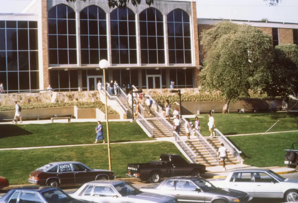 Students on the steps of the Guillot University Center, beneath a row of tall arched windows