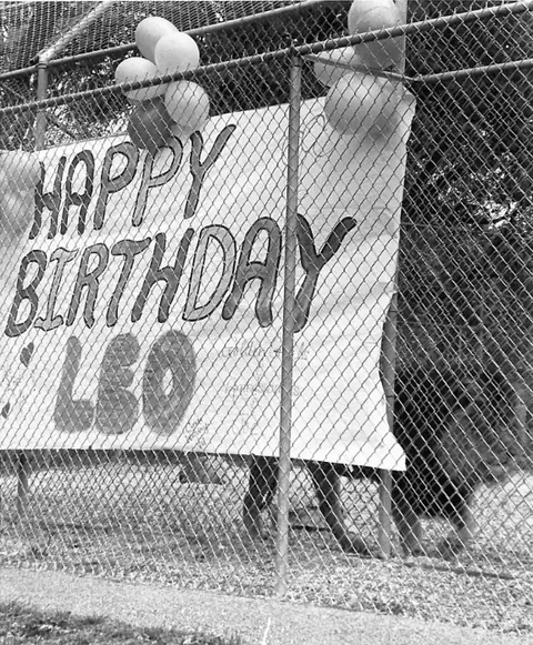 A hand-painted Happy Birthday Leo banner and balloons tied to the fence of Leo&rsquo;s enclosure