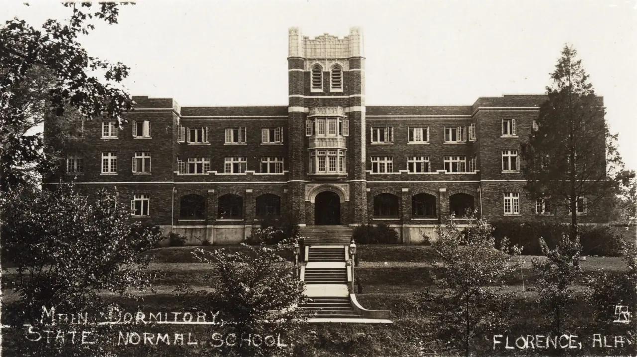 Early postcard of the main dormitory at State Normal School in Florence, a long three-story brick building with a central tower
