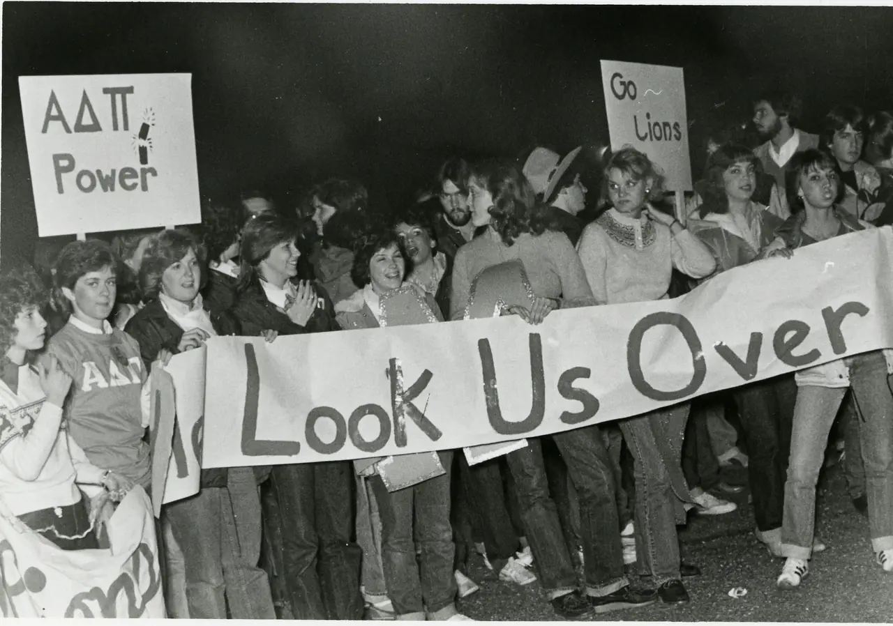Alpha Delta Pi members holding a banner reading Look Us Over, under signs reading Go Lions