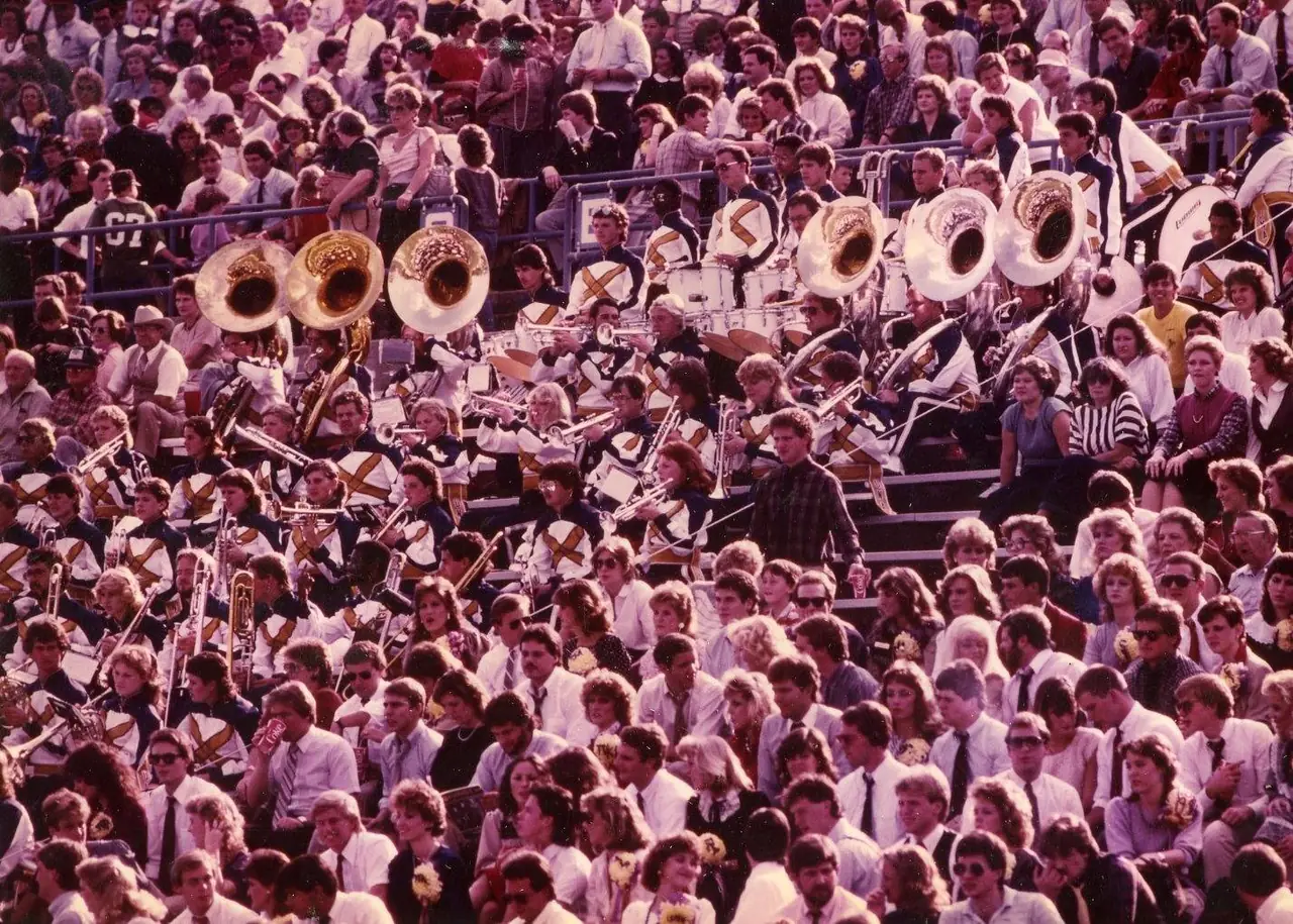 The UNA band in white and purple uniforms, playing from the stands