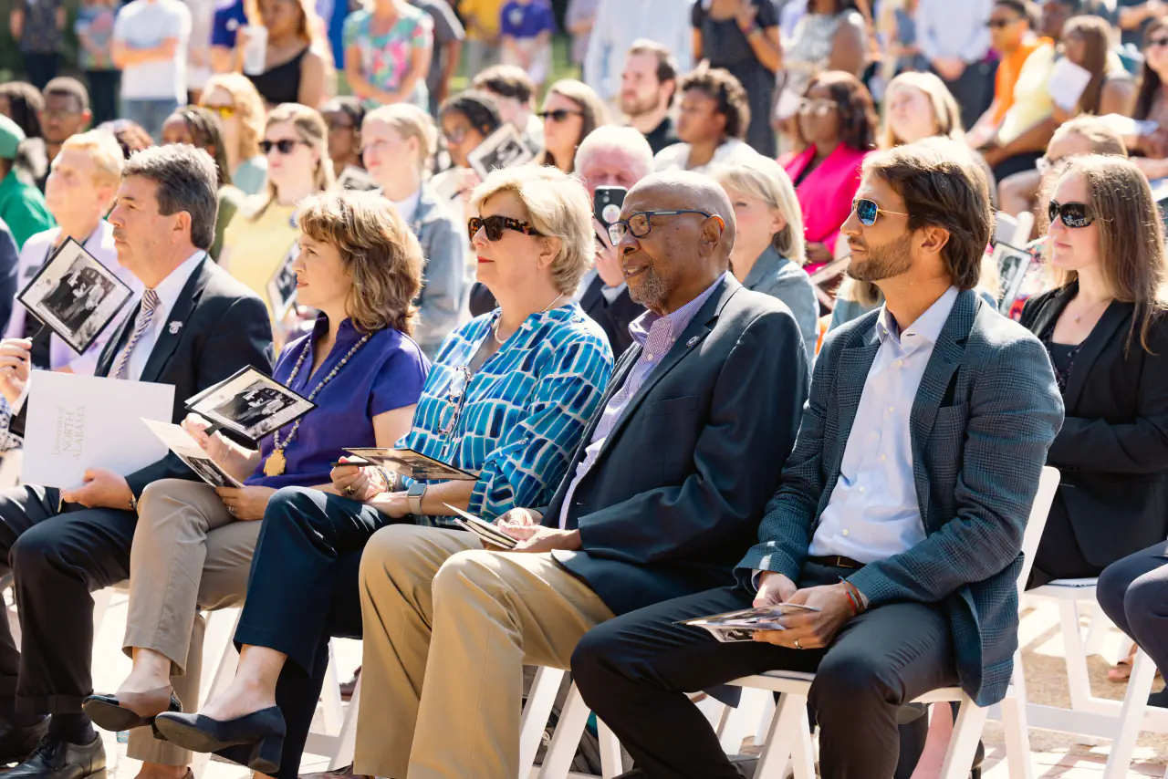 Guests seated in the front row of the outdoor ceremony, programs in hand